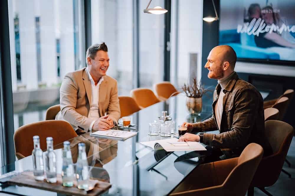 Zwei Männer sitzen an einem Tisch und unterhalten sich.
