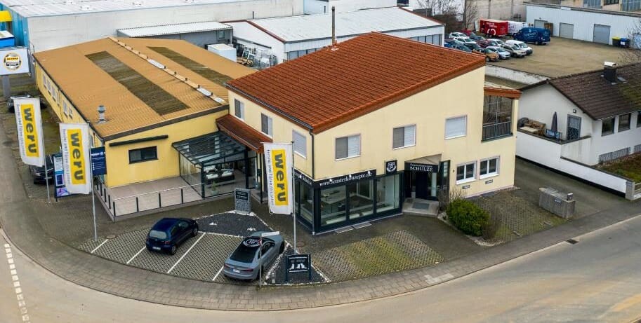 Luftaufnahme eines Weru-Firmengebäudes mit zwei Autos auf dem Parkplatz.