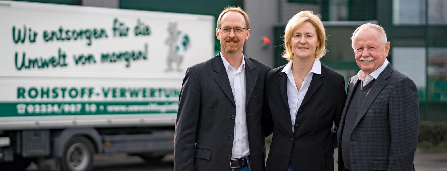 Drei Personen stehen vor einem LKW mit dem Schriftzug "Wir entsorgen für die Umwelt von morgen! Rohstoff-Verwertung".