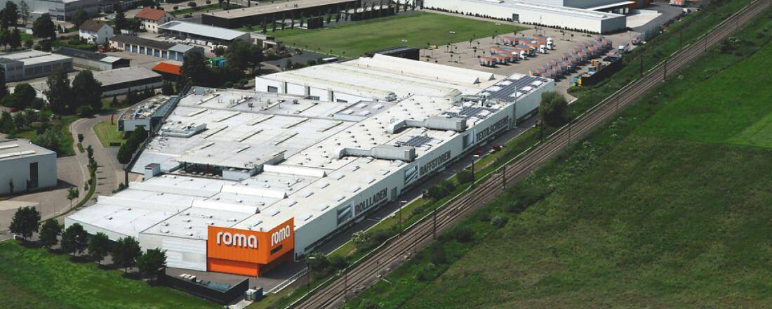 Luftaufnahme eines großen, weißen Gebäudes mit dem Schriftzug "roma" und "rollladen".