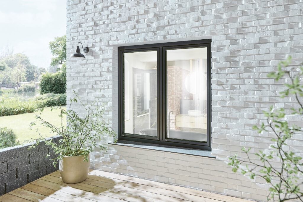 alt="Hochwertiges Kunststofffenster mit dunklem Rahmen in moderner weißer Klinkerfassade – ideal für energieeffiziente Renovierung und langlebige Wärmedämmung"