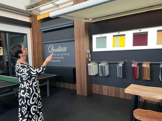 Seniorenpaar unter halb ausgefahrener Markise beim Nachmittagskaffee im Schatten